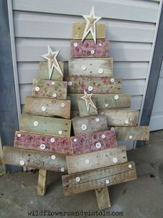 a christmas tree made out of wooden planks with white stars on top and pink flowers