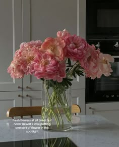 pink flowers are in a clear vase on a kitchen countertop with an inspirational quote