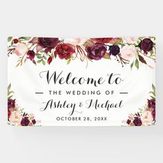 a welcome sign with burgundy flowers and greenery on the front, in white paper