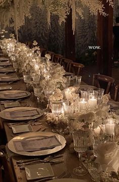 a long table is set with candles and plates for an elegant wedding reception at night