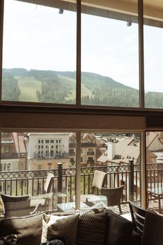 a living room filled with furniture and large windows overlooking a town below it on a sunny day