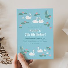 someone holding up a birthday card with swans on it