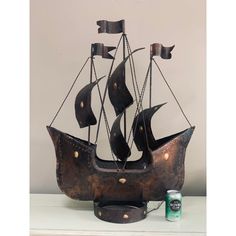 a metal boat is sitting on a shelf next to a can of beer and some tin cans