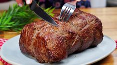 a person cutting into a piece of meat with a knife and fork on a plate