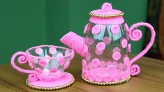 two pink glass teapots sitting on top of a wooden table