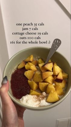 a person holding a bowl of fruit and yogurt with a spoon in it