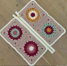 two crocheted squares are sitting on the floor