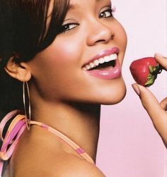 a woman holding a strawberry in her right hand