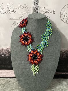 a necklace made with beads and flowers on a mannequin