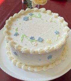 a large white cake sitting on top of a table next to a vase filled with flowers