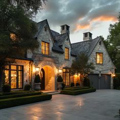 a large house with lots of windows and lights on it's front entrance at dusk