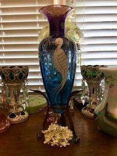 a blue glass vase sitting on top of a wooden table next to other glassware