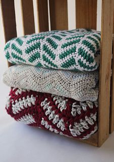 three crocheted blankets stacked on top of each other in a wooden chair frame