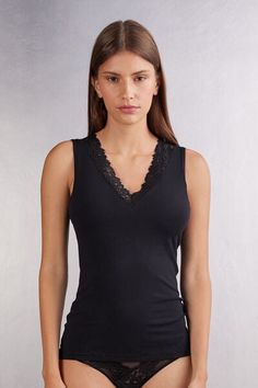 Soft modal tank top with neckline trimmed with an elegant floral motif lace ruffle. Elegant Sleeveless Lace Top With Built-in Bra, Elegant V-neck Tank Top With Lace Trim, Feminine Stretch Tank Top With Lace Trim, Chic Sleeveless Tops With Delicate Lace, Elegant Delicate Lace Tank Top For Daywear, Elegant V-neck Seamless Tank Top, Elegant Stretch Vest Tops, Feminine Lace Trim Tank Top, Elegant Seamless Tank Top For Spring