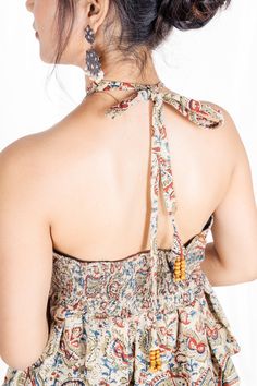 Unleash your adventurous spirit and make a statement with the Dancing Paisley Halter! Made with organic cotton and featuring a bold Kalamkari block print, this top is both eco-friendly and eye-catching. The unique mango beads at the end of the straps and back scrunching provide a perfect fit, while the frill adds a playful touch. 🌟 A bold holiday look! 🌟 Model is wearing XS size. 🌟 Complete the outfit with Dancing Paisley Flare Pants for a total wow factor. 🌟 Bohemian Tie Back Top For Festival, Bohemian Cotton Tops With Adjustable Straps, Cotton Bohemian Halter Top For Festivals, Bohemian Cotton Halter Neck Top, Festival Halter Top With Adjustable Straps, Multicolor Cotton Halter Top For Festival, Bohemian Multicolor Tie Back Top, Bohemian Tie-back Halter Top For Vacation, Bohemian Multicolor Tie-back Top