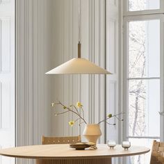 a dining room table with two chairs and a vase on the table next to it