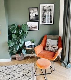 an orange chair and ottoman in a living room next to a green wall with pictures on it