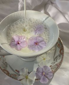 a cup filled with water and flowers on top of a saucer