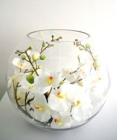 there is a glass bowl with white flowers in it