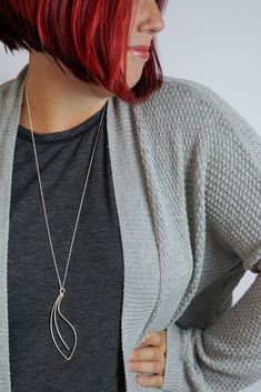 Soft curves form an elegant, handcrafted pendant on a long chain for the perfect pop for your every day style. Available in tarnish-resistant Argentium silver with a silver chain, matte black steel with an oxidized silver chain, or bronze with a bronze chain. Approximately 3 1/2" tall and 1 1/8" wide. Comes on a 30" long chain with clasp. Each necklace is handmade to order and may vary slightly from those shown. Please allow 2-3 days for your necklace to ship. Comes in a gift box tied with a rib Everyday Oxidized Metal Necklace, Minimalist Gunmetal Metal Necklace, Modern Gunmetal Necklace With Oxidized Finish, Elegant Stainless Steel Necklace With Oxidized Finish, Argentium Silver, Oxidized Silver, Long Chain, Black Steel, Long Necklace