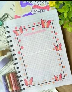 an open notebook with butterflies on it next to crayons, markers and pencils