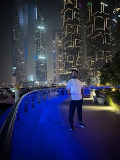 a man standing on the edge of a bridge in front of tall buildings at night