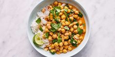 a white bowl filled with rice, chickpeas and cilantro on top of a marble table