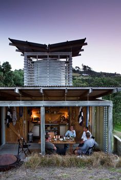 some people are sitting at a table in front of a building with an open roof