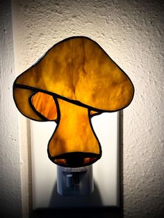 a lamp that is sitting on top of a table next to a white wall with a mushroom shaped light in it