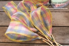 two yellow and pink plaid cloth flowers on a wooden table next to a teapot