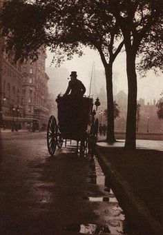 an old photo of a man riding in a horse drawn carriage