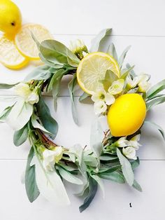 a wreath made out of lemons and flowers on a white surface with leaves around it