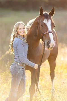 a beautiful young woman standing next to a brown horse