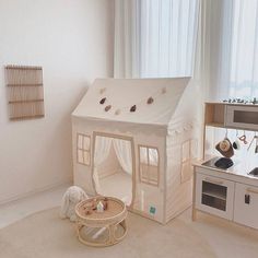 a doll house in the middle of a playroom with toys on the floor and around it