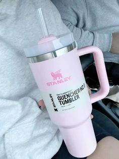 a person holding a pink tumbler cup in their hand while sitting on a car seat