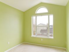 an empty room with green walls and white trim on the windowsill, carpeted floor