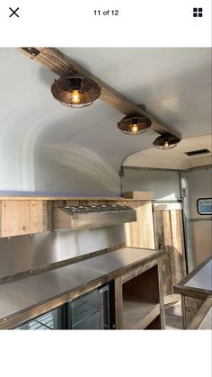 the inside of a trailer with lights on and wood beams hanging from it's ceiling