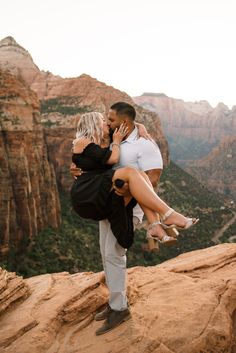 a man holding a woman on top of a mountain