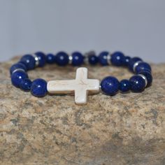 Hope Angel Bracelets This cross bracelet can be worn with anything and it carries such special meaning. It was made with Lapis Lazuli beads in two sizes with pewter charms as accent beads. The cross is made of howlite and lays flat on your wrist. On the back of the bracelet is small Hope Angel Bracelet hang tag. This understated bracelet is perfect for any occasion, and will uplift your spirit. The cross is a symbol of hope, the love of Jesus, and the ultimate sacrifice. Let this bracelet remind Adjustable Cross Stretch Bracelet As Gift, Adjustable Cross Jewelry With Natural Stones, Adjustable Cross Stretch Bracelet Spiritual Style, Spiritual Style Cross Beaded Bracelets For Gift, Handmade Spiritual Beaded Bracelets With Cross, Spiritual Cross Beaded Bracelets For A Gift, Nickel Free Cross Bracelet With Spiritual Style, Spiritual Cross Beaded Bracelets As Gift, Spiritual Adjustable Cross Beaded Bracelets