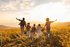 a group of people walking across a grass covered field with their arms in the air