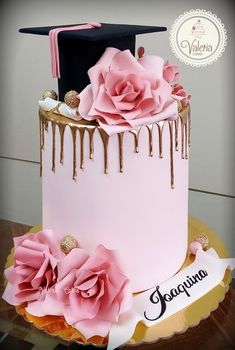 a pink and gold graduation cake with chocolate drips on the top is decorated with flowers