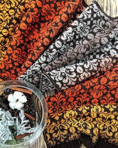 three knitted blankets sitting next to each other on top of a wooden table with cotton balls