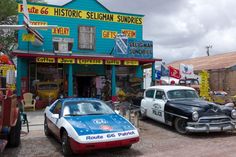 an old fashioned police car parked in front of a store with other antique cars outside