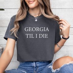 *Also available as a sweater. See below.* Show your love for the Georgia Bulldogs with this Georgia Til I Die t-shirt! Perfect for the true fan, this shirt will keep you looking stylish while showing off your team spirit. Show everyone that you're a fan for life with this must-have shirt. Cotton Slogan T-shirt For Fan Gear, Cotton Team Spirit T-shirt With Slogan, Collegiate Cotton T-shirt With Slogan, Game Day Graphic Tee With Slogan, College Fan Apparel T-shirt With Slogan, Graphic Tee With Slogan For Game Day, Fan Apparel Tops With Slogan, Game Day Slogan Graphic Tee, Relaxed Fit T-shirt With Text Print For Fans