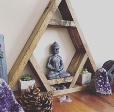 there is a small buddha statue on the shelf next to some rocks and pine cones