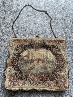 "This is a beautiful vintage French antique circa 1930 Petit pointe brocade evening bag.  The piece appears to be a cotton brocade featuring a river scene surrounded by flowers. The image is the same on both front and back. The inside has a satin lining and a tag that says made in France. The body of the Purse measures 5 1/2\" x 6 1/2\"  The frame measures 6 1/4 inches and it's 2 inches deep The chain measures 13 inches. Overall this item is in very good condition. There  is some wear to the bra Vintage Evening Bag In Tapestry Material, Vintage Tapestry Bag For Evening, Vintage Formal Tapestry Bag, Vintage Tapestry Bag For Formal Occasions, Formal Vintage Tapestry Bag, Vintage Tapestry Shoulder Bag For Evening, Vintage Tapestry Pouch Bag, Antique Tapestry Evening Bag, Antique Tapestry Bags For Everyday