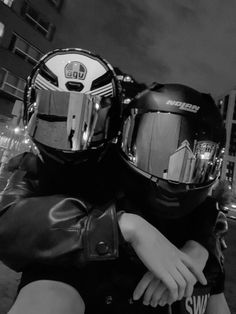 black and white photograph of two people wearing helmets on their backs, one holding the other