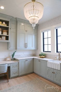 a kitchen with light green cabinets and white counter tops, an area rug and a chandelier hanging from the ceiling