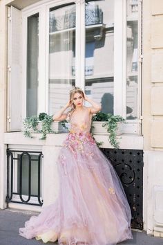 a woman in a pink dress leaning against a window