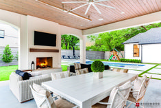 an outdoor dining area with fireplace and television